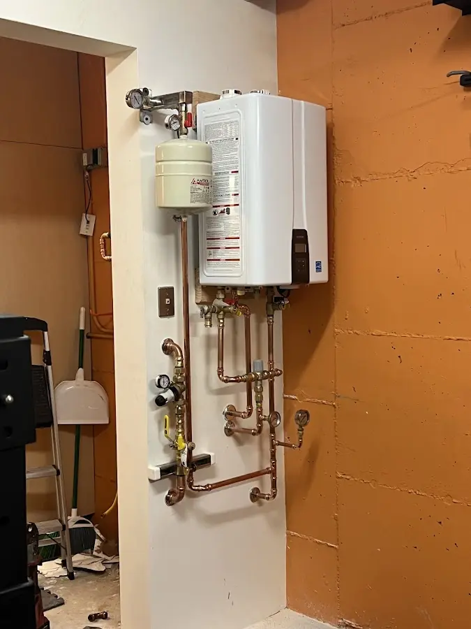 Plumbing technician inspecting water heater connections in Southold